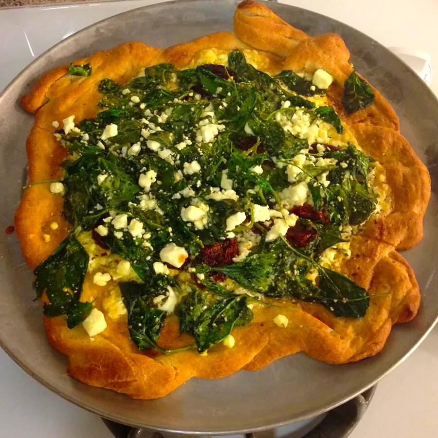 Greek-style pizza featuring a delicious combination of spinach, feta cheese, and olives.