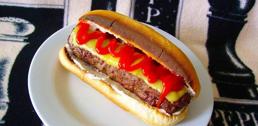 Cover Image for The All-American Burger Dog combines two iconic American favorites: the classic burger and the fun shape of a hot dog.